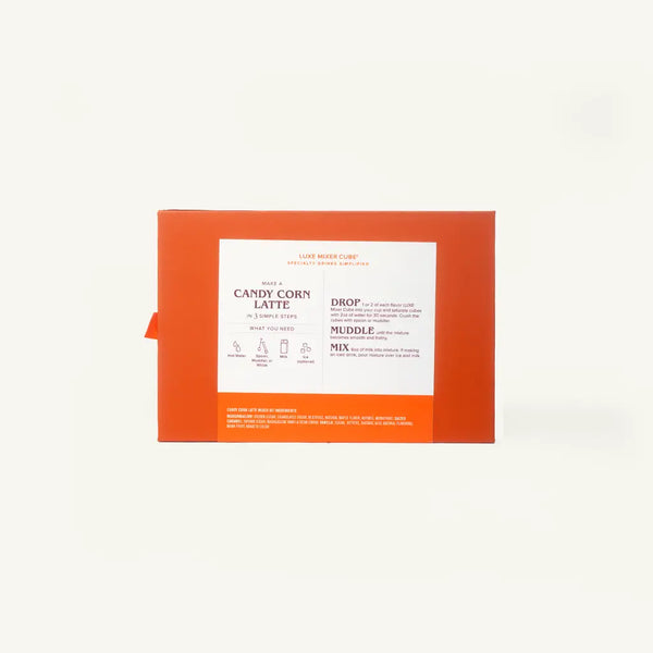 An orange cardboard box for a 'Candy Corn Latte' by LUXE Mixer Cube, featuring a white instructional label with text and diagrams, set against a plain off-white background.