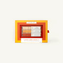 A boxed set of three coffee-flavored candy corn lattes in a bright orange and yellow window box package, photographed against a plain off-white background.