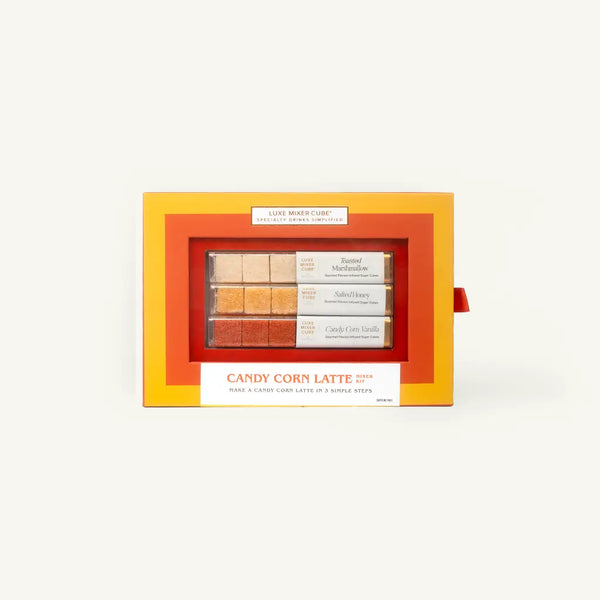 A boxed set of three coffee-flavored candy corn lattes in a bright orange and yellow window box package, photographed against a plain off-white background.