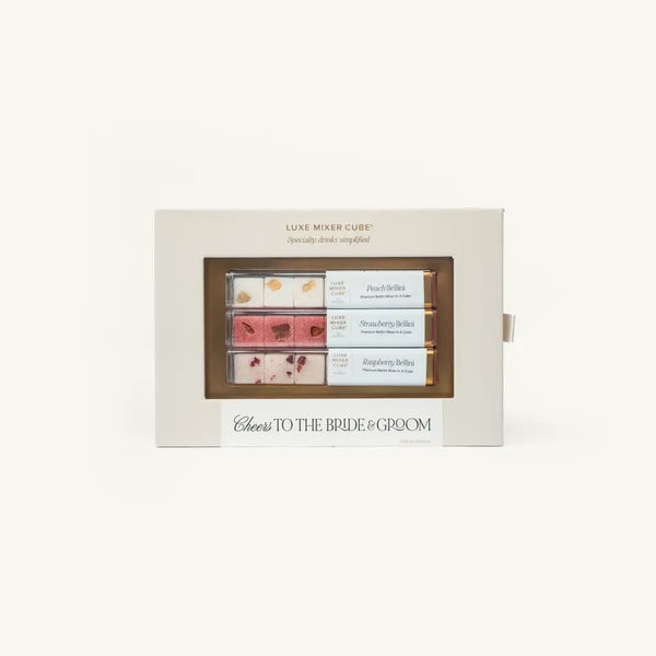 Box of Luxe Mixer Cubes labeled Cheers to the Bride & Groom, containing three flavors: Peach Bellini, Strawberry Bellini, and Raspberry Bellini, each visible through a clear window. White background.