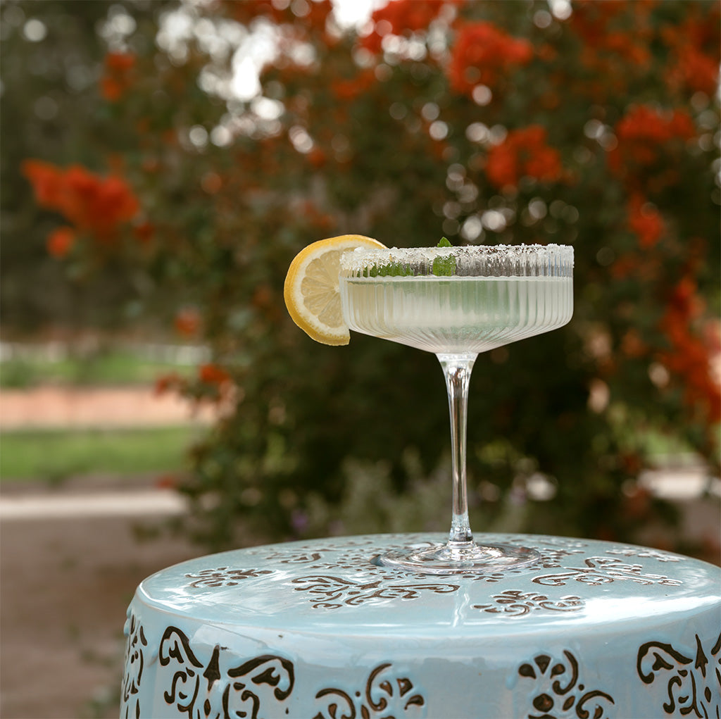 Cocktail with a lemon wedge on a decorative table outdoors