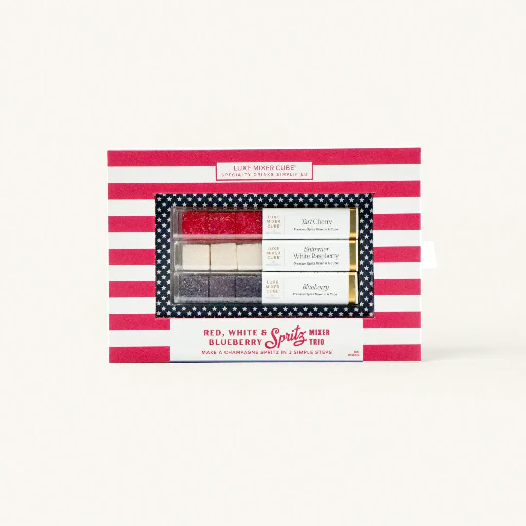A boxed set of Luxe Mixer Cubes featuring three flavors: Tart Cherry, Shimmer White Raspberry, and Blueberry, designed for making specialty drinks. The box has a red and white striped design with blue star accents.