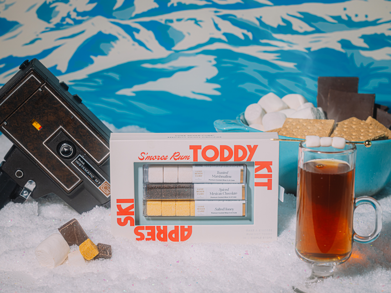 Smores rum Toddy Kit with a glass of liquid on a snowy background