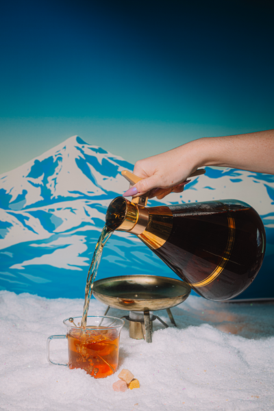 Person pouring tea into a cup with a mountainous background