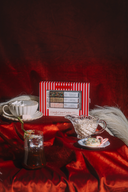 Red and white striped box with a tea set on a red fabric background