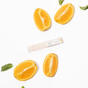 Sliced orange halves arranged around a packaging label for "Luxe Mini", with mint leaves.