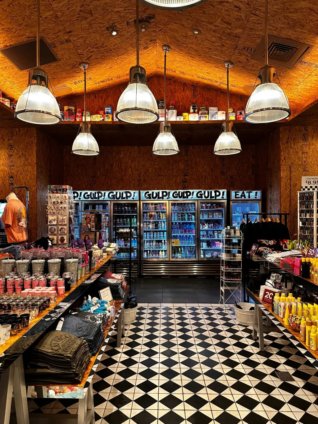 Interior of a store with a checkered floor, shelves stocked with products, and hanging lights.