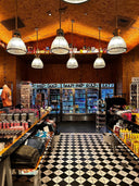 Interior of a store with a checkered floor, shelves stocked with products, and hanging lights.