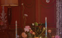 Decorative table setting with flowers, candles, and a lamp against a red wall.